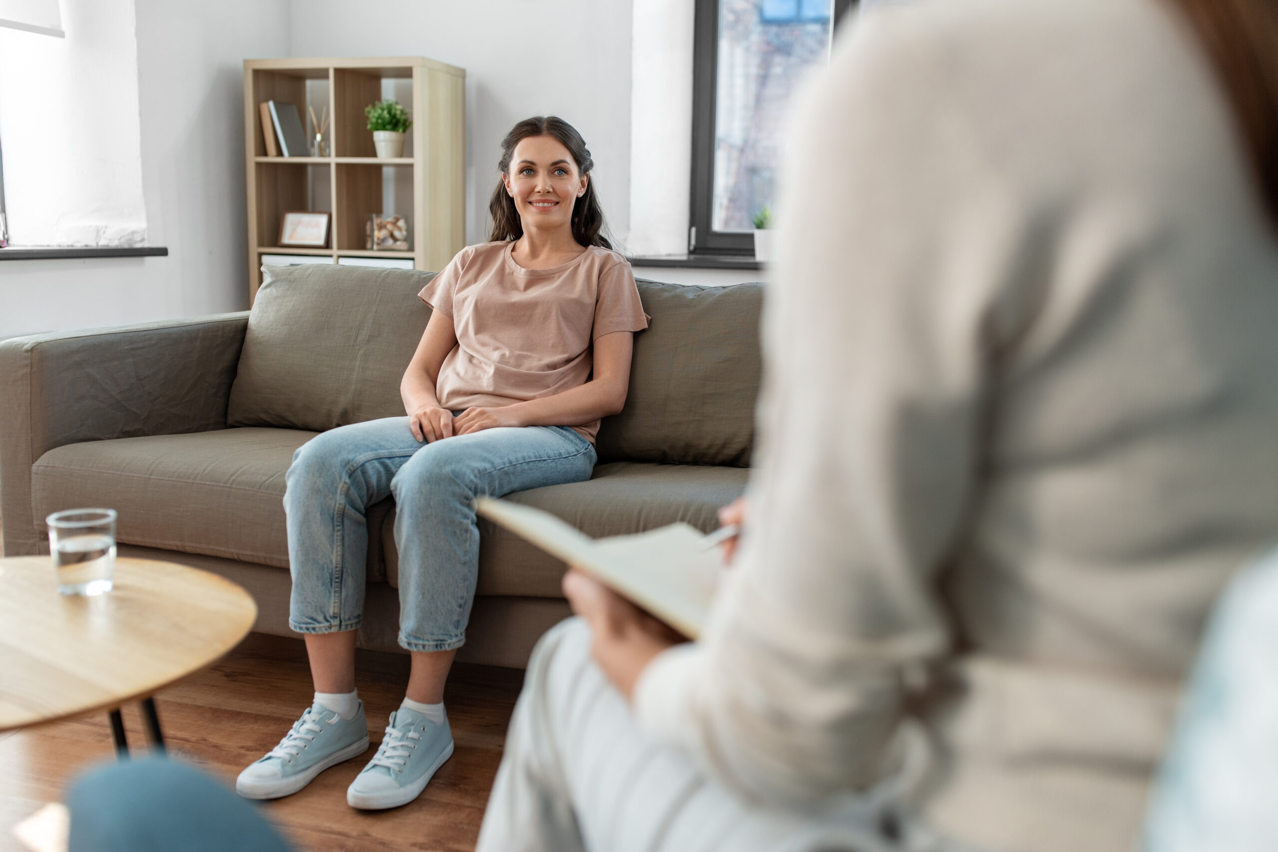 psychology, mental health and people concept - happy smiling young woman patient and woman psychologist at psychotherapy session